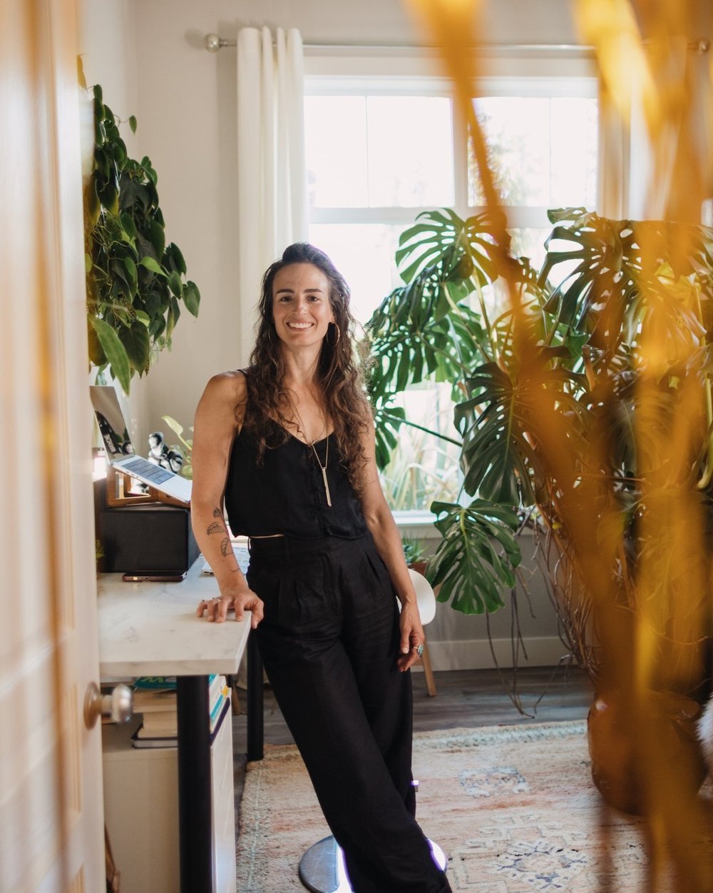 Bonnie Weeks standing in her office wearing a black top and black pants. She is smiling at the camera. 